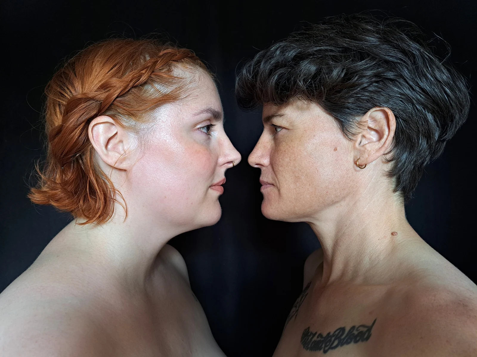 Deux femmes, l’une rousse et l’autre brune, se regardent de profil.