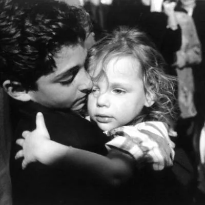En noir et blanc, un jeune homme serre une petite fille contre lui