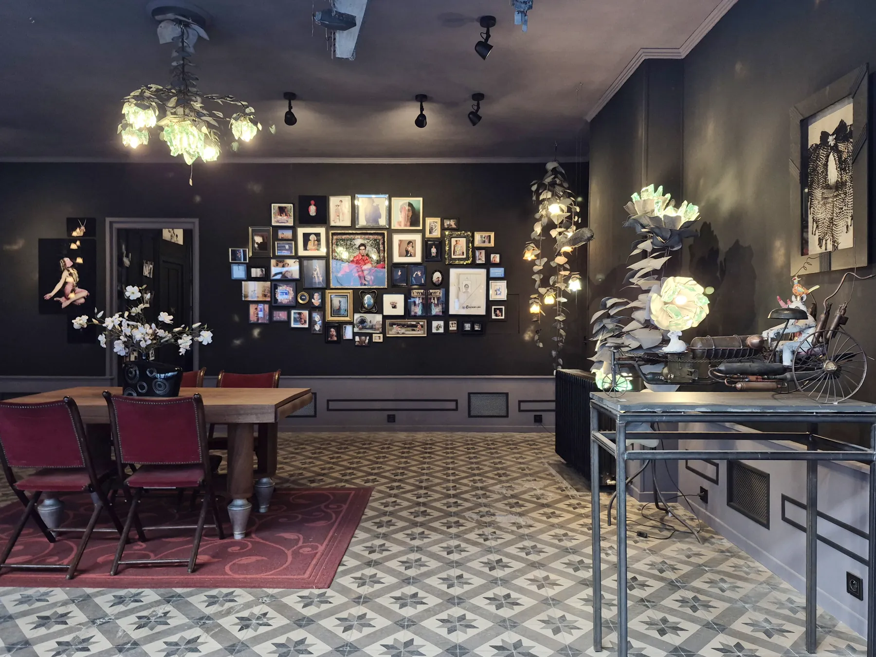 La galerie Lune de Verre : murs noirs couverts de photographies encadrées, luminaires sculptés